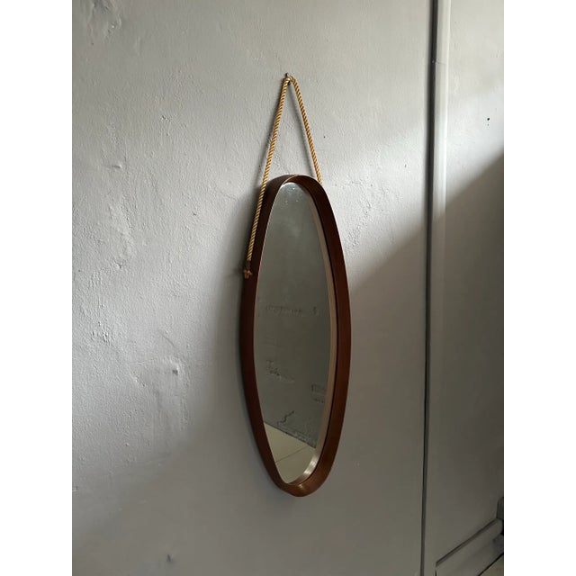 Vintage oval mirror, with 1960's teak frame, Italian manufacture. The mirror has a rope to hang it on the wall