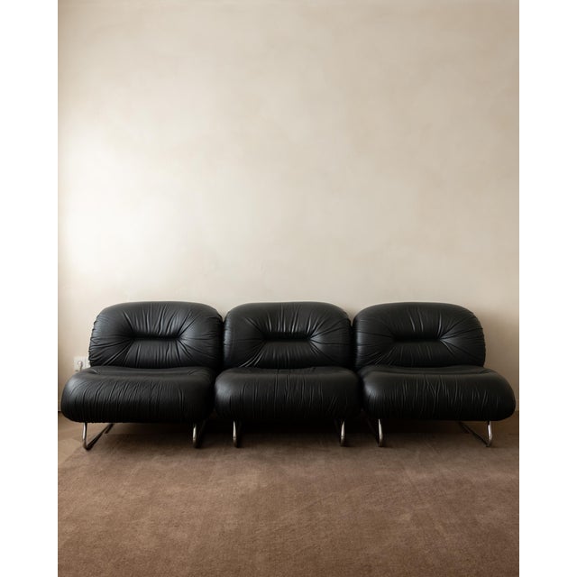 A vintage set of three italian lounge chairs in black leather and polished chrome-plated tubular steel, produced in italy...