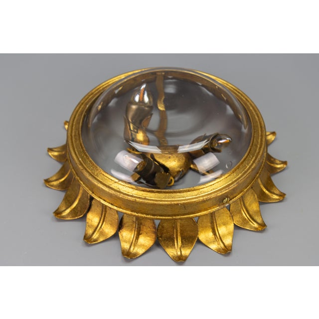 Hollywood Regency style gilt metal and clear glass three-light flush mount or wall light from the 1950s, Germany. This...