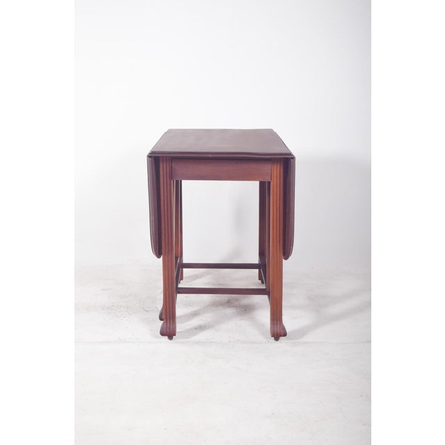 A leaf-shaped table with an oval top. with elegantly curved legs supporting the structure, it features a fixed central...