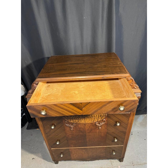 Striking Art Deco Waterfall chest of drawers featuring classic rounded top edges, bold veneer inlay, and carved scroll...