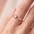 A bold, contemporary open-cuff ring featuring two soft blush rose quartz stones — an oval-cut stone paired with a round-...