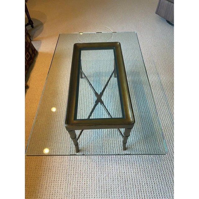 Rectangular glass top cocktail table with gilt faux bamboo base. A long rectilinear cocktail table with a thick glass top...