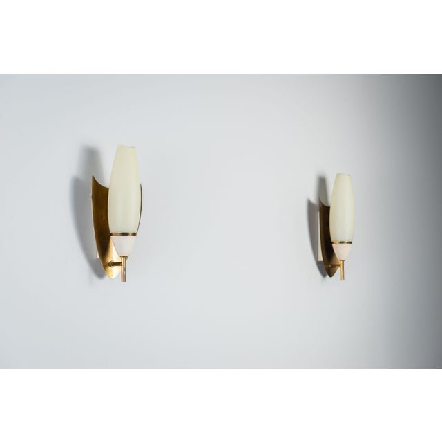 This elegant pair of vintage wall lamps showcases a refined mid-century aesthetic, combining warm brass shield backplates...