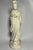 An elegant white porcelain figure of a lady holding a fan, distinguished by her softly lowered gaze, elaborate coiffure,...