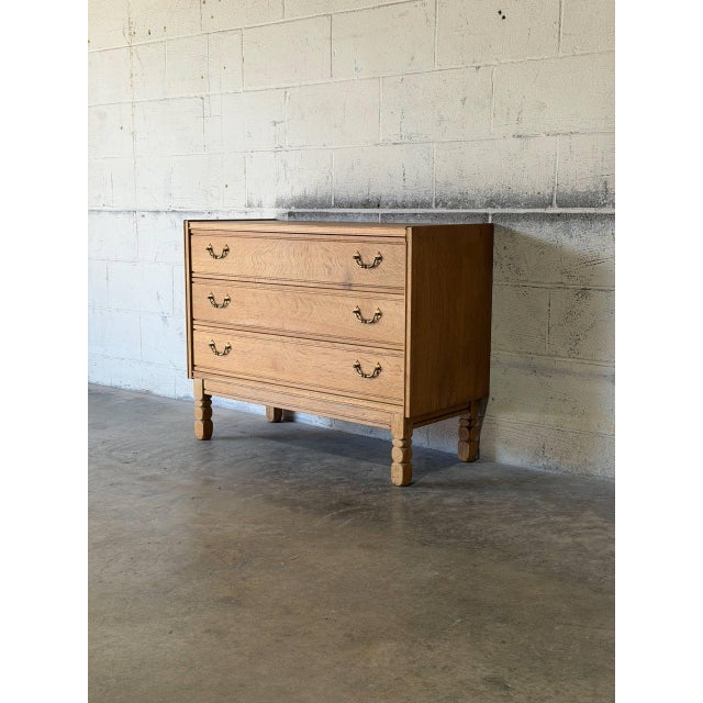 This refined chest features three spacious drawers set on carved turned legs. The top drawer opens to reveal green felt-...