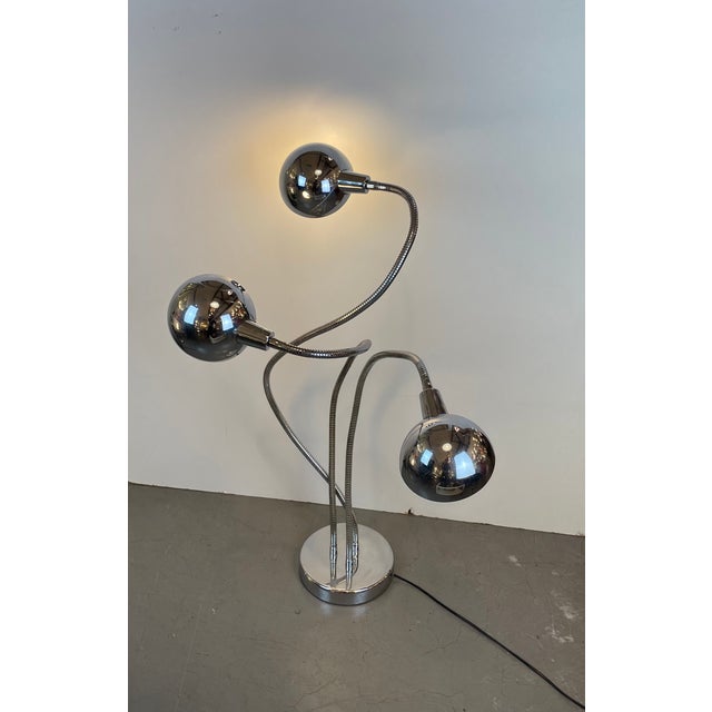Sculptural Space Age floor lamp crafted in chrome-plated metal, featuring a weighted circular base and three flexible...