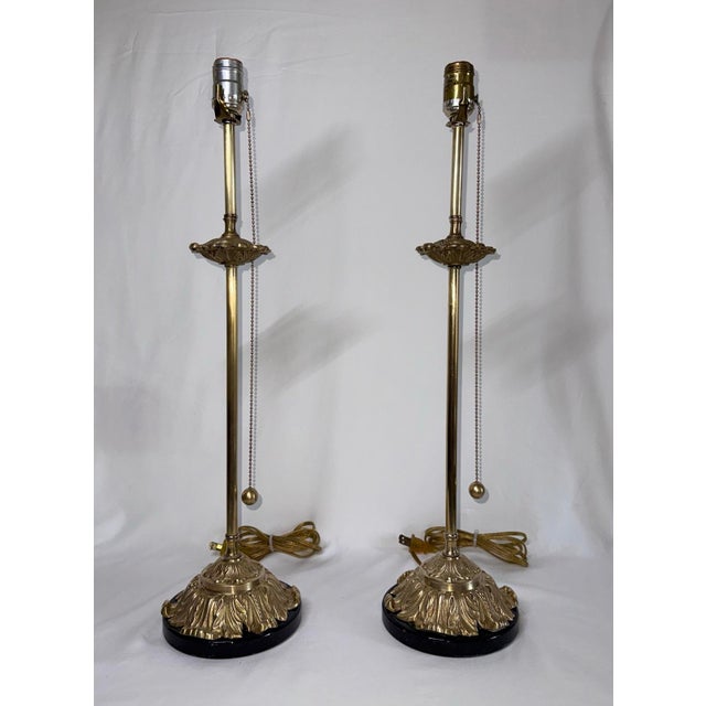 Pair of antique brass acanthus leaf tall buffet table lamps with brass pull chains and black marble bases. The long pull...