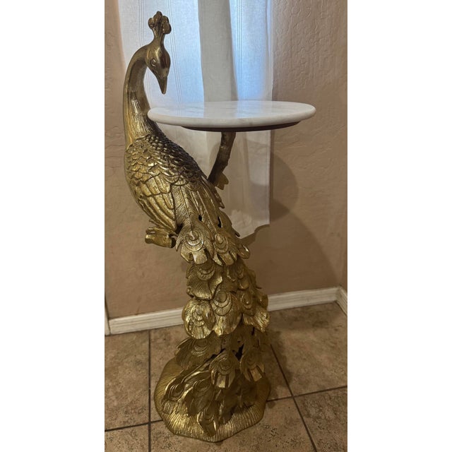 Side table with golden peacock base and round marble top. Maker unknown. Great condition. 30” height to crown of peacock....
