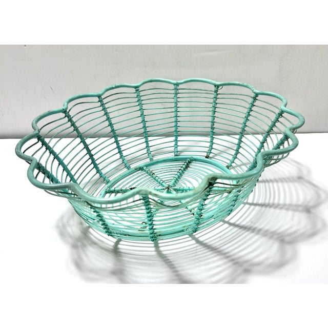 Vintage turquoise wire basket with a scalloped flower-shaped rim and an open concentric wire pattern. Its shallow bowl...
