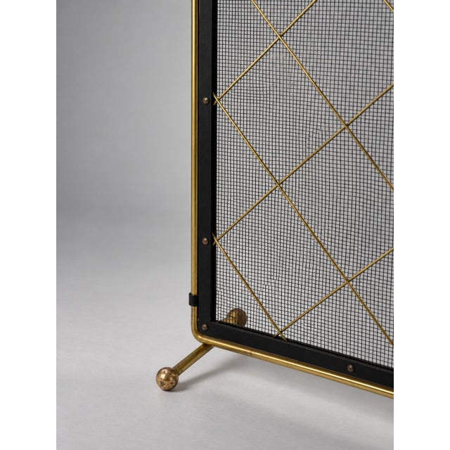 An elegant vintage fireplace screen combining refined geometric detailing with a striking contrast of black metal and warm...