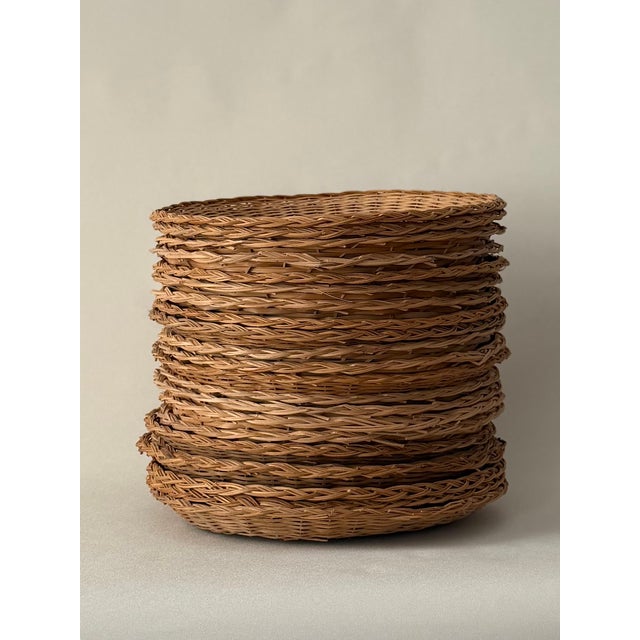 Set of twenty-two hand-woven natural wicker or rattan charger plates. Light honey-golden tone; tight weave throughout....