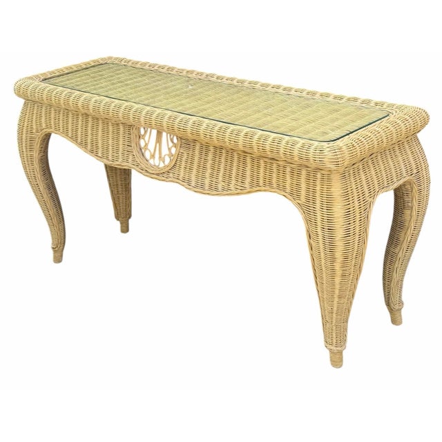 Vintage rattan console table with a sculptural silhouette, curved legs, woven construction, and a decorative circular...