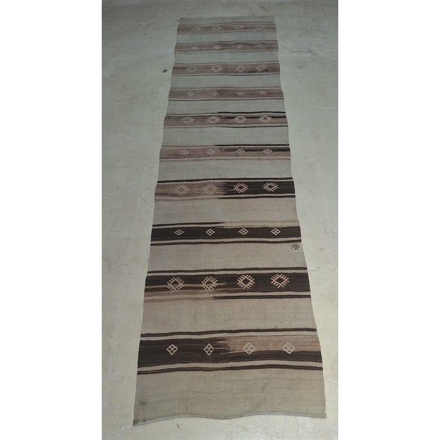 Vintage Navajo-style handwoven wool runner featuring a warm neutral palette of ivory, tan, brown, and deep charcoal. The...