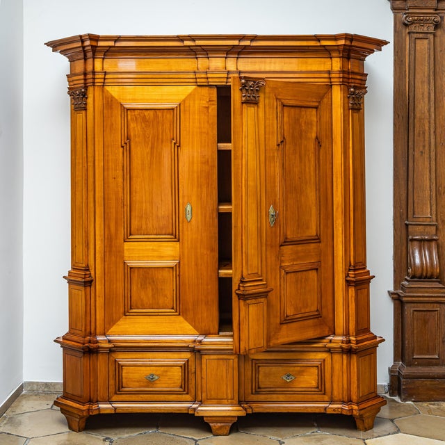 Large hall cabinet in cherrywood with two doors and two drawers in the tall plinth section. The structure is articulated...