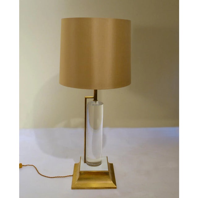 Mid Century Hollywood Regency style table lamp has a acrylic glass cylinder stem supported with a brass tume and base with...