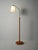 Mid-century Scandinavian floor lamp with a round base on small feet, an oak stem, and a metal neck with an adjustable...
