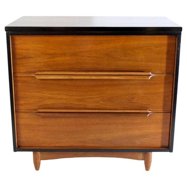 An elegant dresser in teak with an ebonized frame. It has four spacious drawers with handles that are incorporated curved...