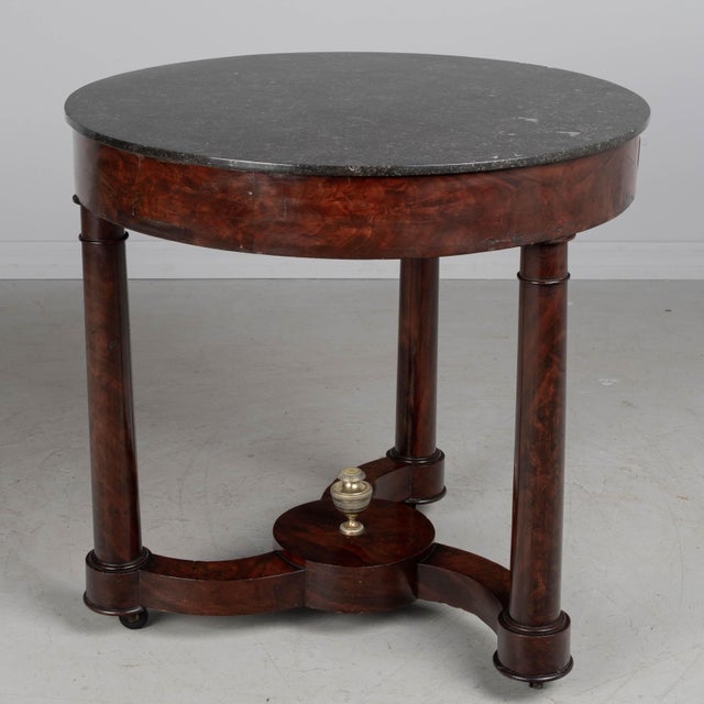 A 19th century French Empire Period mahogany gueridon, or game table, with Grey St. Anne marble top. A versatile table...