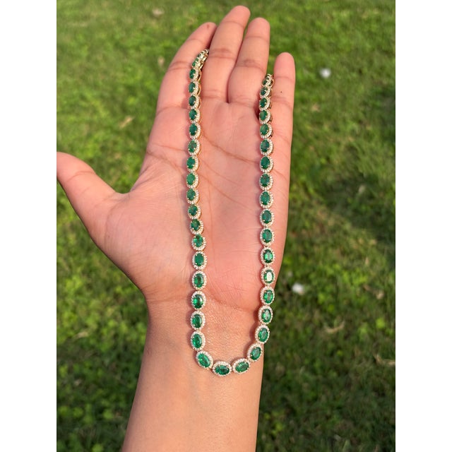 This tennis necklace features a 22.13 carat oval-cut emeralds and diamond, set in 18k yellow gold. The emeralds measure...