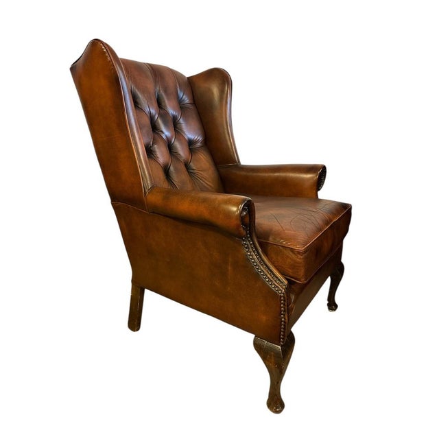 Vintage English wingback armchair in cognac-brown leather with deep-button tufting and nailhead trim. Featuring Queen Anne...