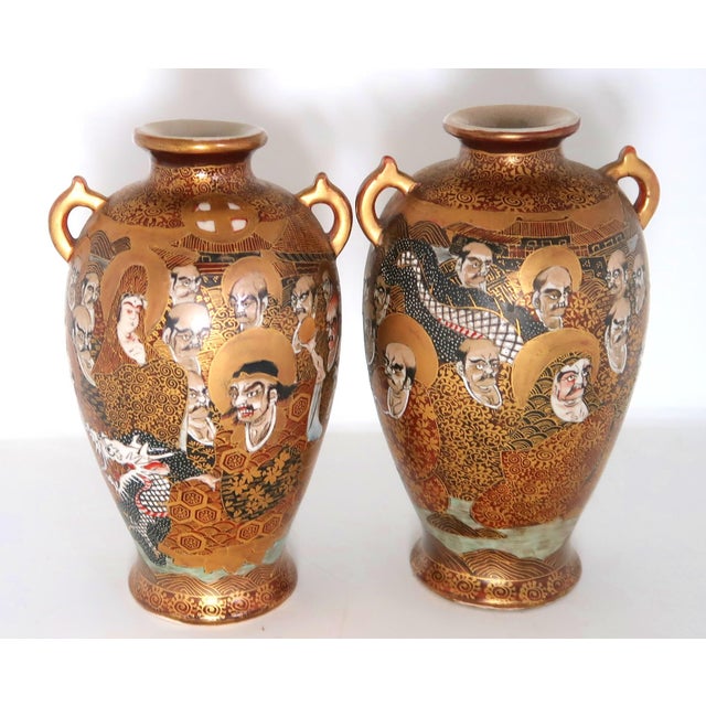 Heavily gilded matched pair of antique Japanese porcelain satsuma vases. Interesting and varied faces all around, with...