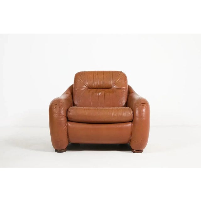 Italian mid-century modern sculptural armchair in brown cognac leather, produced in 1960's. Condition Fair, age related...