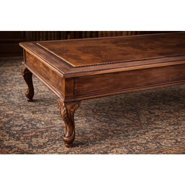 This elegant coffee table features a richly detailed leather inset top adorned with a vintage-style world map motif,...