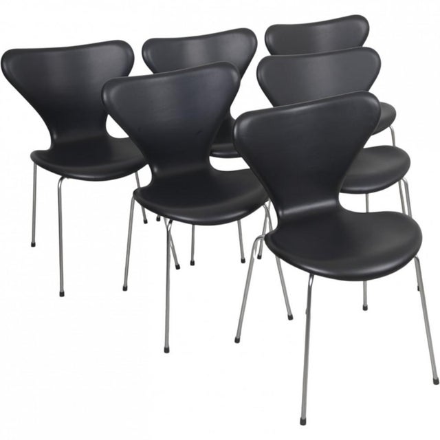 Set of 6 Arne Jacobsen Seven chairs with matt frame and fully upholstered inblack classic leather. The chairs appear with...
