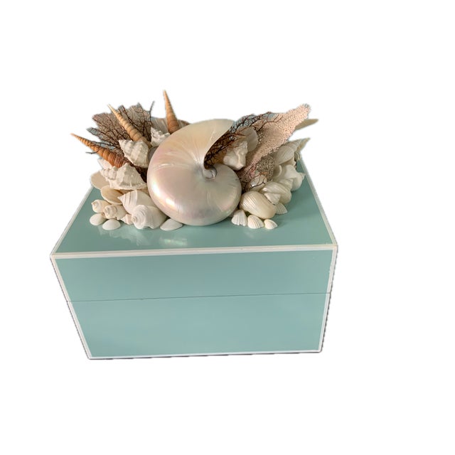 This handmade.keepsake box is adorned with natural seashells and a large mother-of-pearl nautilus shell, offering a...