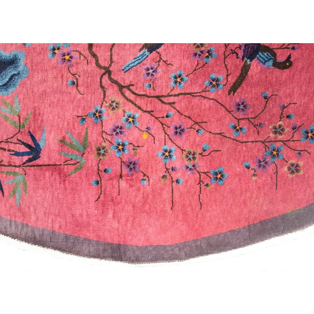 A striking early 20th-century Chinese Art Deco oval rug, woven with a rich and symbolic design. At its heart, a gracefully...