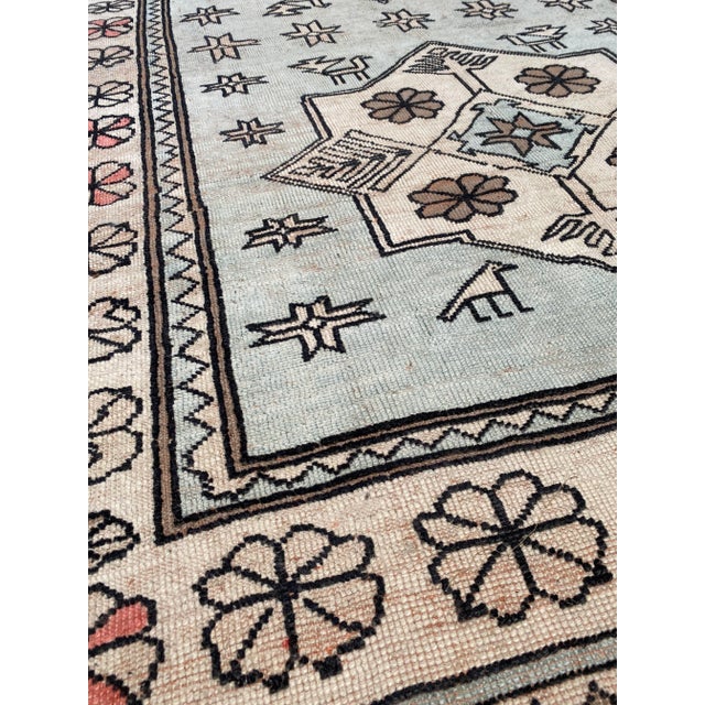 A beautiful vintage Oushak rug. This vintage Oushak offers a muted blue palette with pink and brown accents.