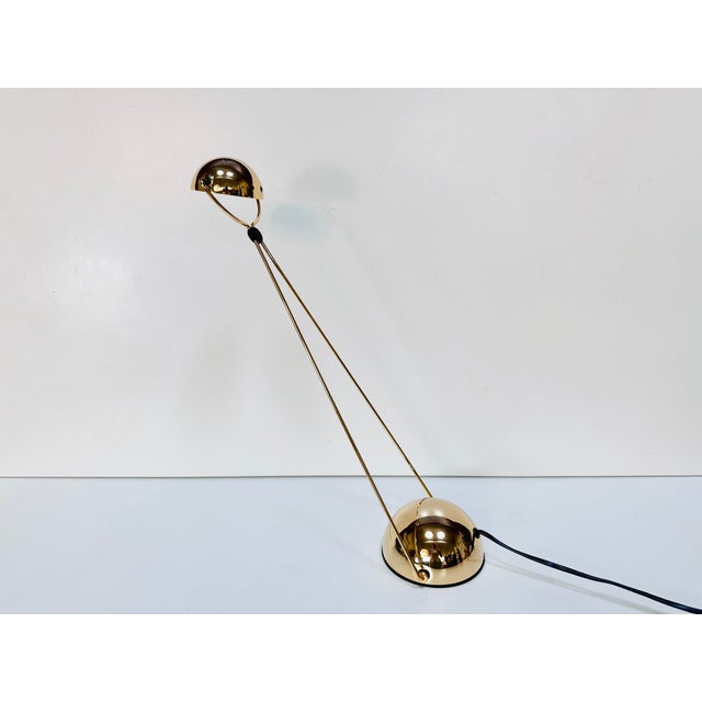 The elegant Meridiana halogen desk lamp—shown here in the rare gold-colored brass version—is an iconic postmodern design...