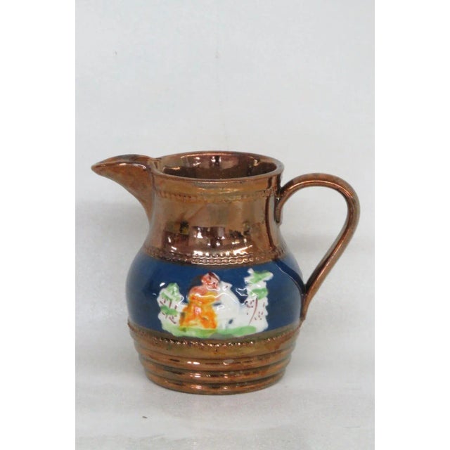 This wonderful small pitcher / creamer is made of ceramic. This piece features a gorgeous copper luster to the exterior...
