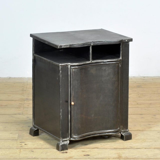 Bedside table from the 1930s with a characterful, industrial look. The cabinet features an elegant, curved front that...