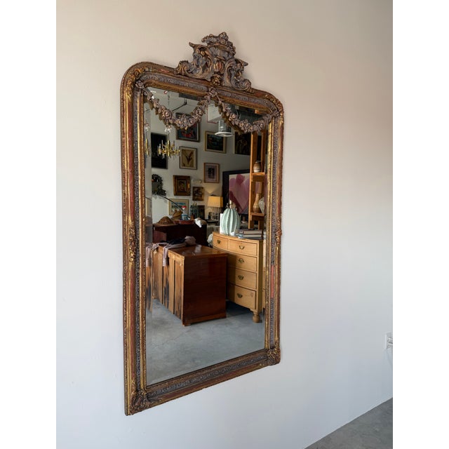 An elegant 19th-century French wall mirror featuring a richly carved giltwood frame in the Rococo taste. The stately...