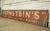 Reclaimed movie set sign made of aluminum in red, green, and white colors. The sign reads "145, Bernstein's, Woolens &...