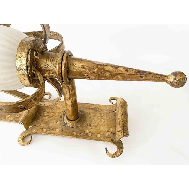 Pair of early to mid century wrought iron wall sconces. Cast and wrought iron with gilt finish and frosted glass shades....