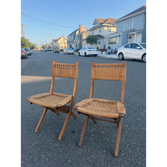 Teakwood and weaved rope folding chairs in the style of Hans Wegner. The chairs are made in Yugoslavia. H: 31.75” W: 17”...