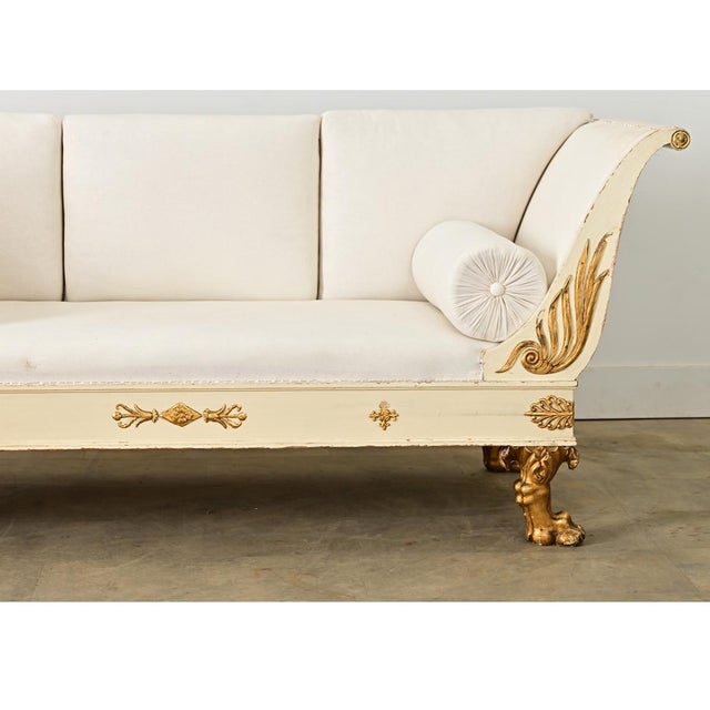 A glamorous Swedish Empire style settee from the early 19th century (circa 1820) its painted wood frame sheltering the...