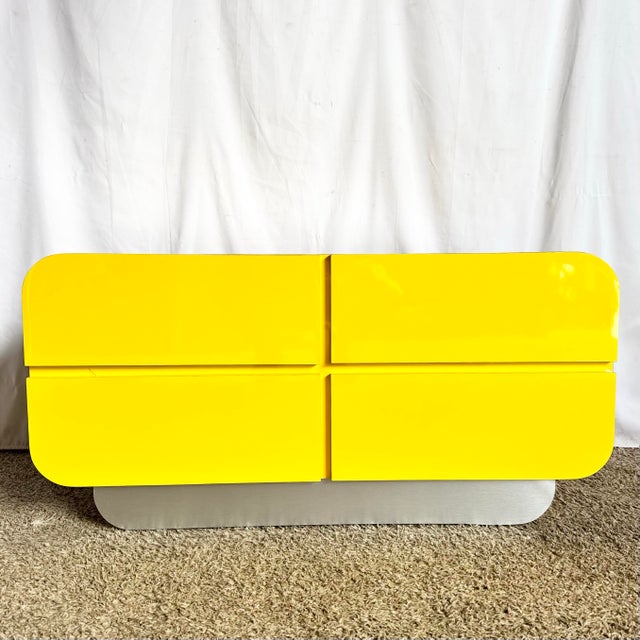 A striking postmodern dresser defined by its sculptural waterfall silhouette and high-gloss yellow laminate finish. The...