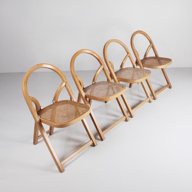 Four Arca folding chairs designed by Gigi Sabadin and produced by Crassevig in the 1970s. Hot-bent solid wood frame,...