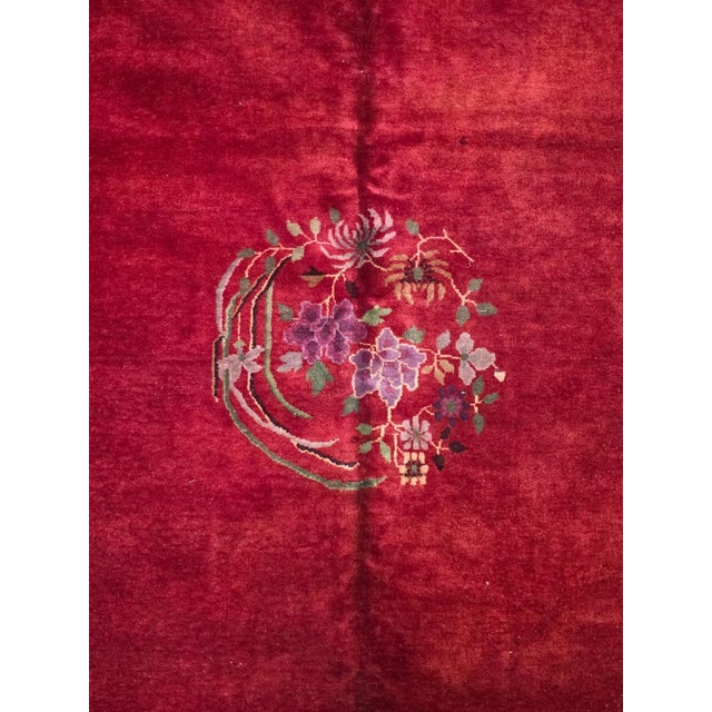 Antique Chinese Art Deco rug, circa 1920s–1930s, featuring a rich crimson red field framed by a deep navy blue border. The...