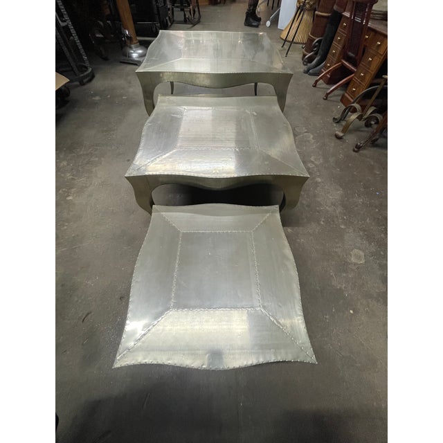 A trio art deco industrial style metal clad nesting coffee tables hand-carved from solid teak wood and covered in a skin...