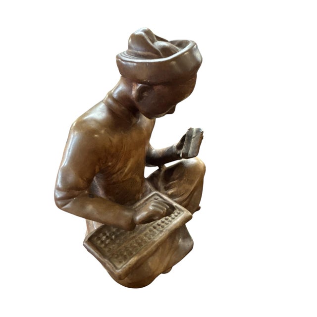 A delightful pair of hand-carved vintage figurines depicting seated scholars engaged in study and calculation. One figure...