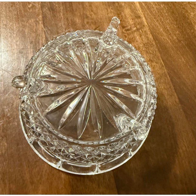 This is a clear glass, three footed dish intricately designed with prominent diamond and starburst patterns. It features a...