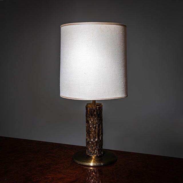 Table lamp by Luciano Frigerio with a brass base and cylindrical fabric shade. The base consists of a disc-shaped foot and...