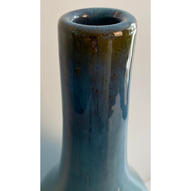 A striking monumental Mid-Century Modern studio pottery vase featuring a graceful bottle-form silhouette with a rich blue-...