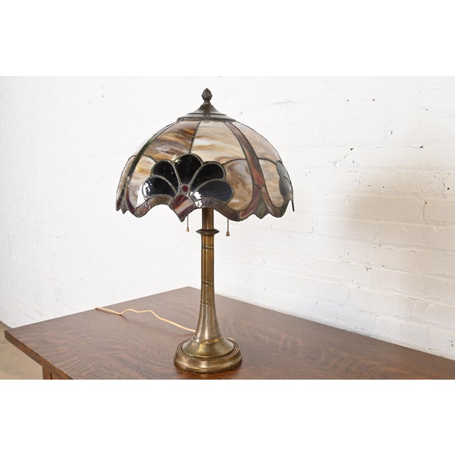A gorgeous Arts & Crafts stained glass table lamp In the manner of Tiffany Studios USA, Circa 1930s Bronze base, with...