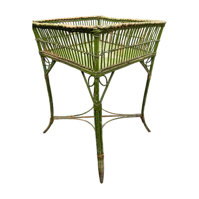 A green painted wicker plant stand with square basket style gallery.
